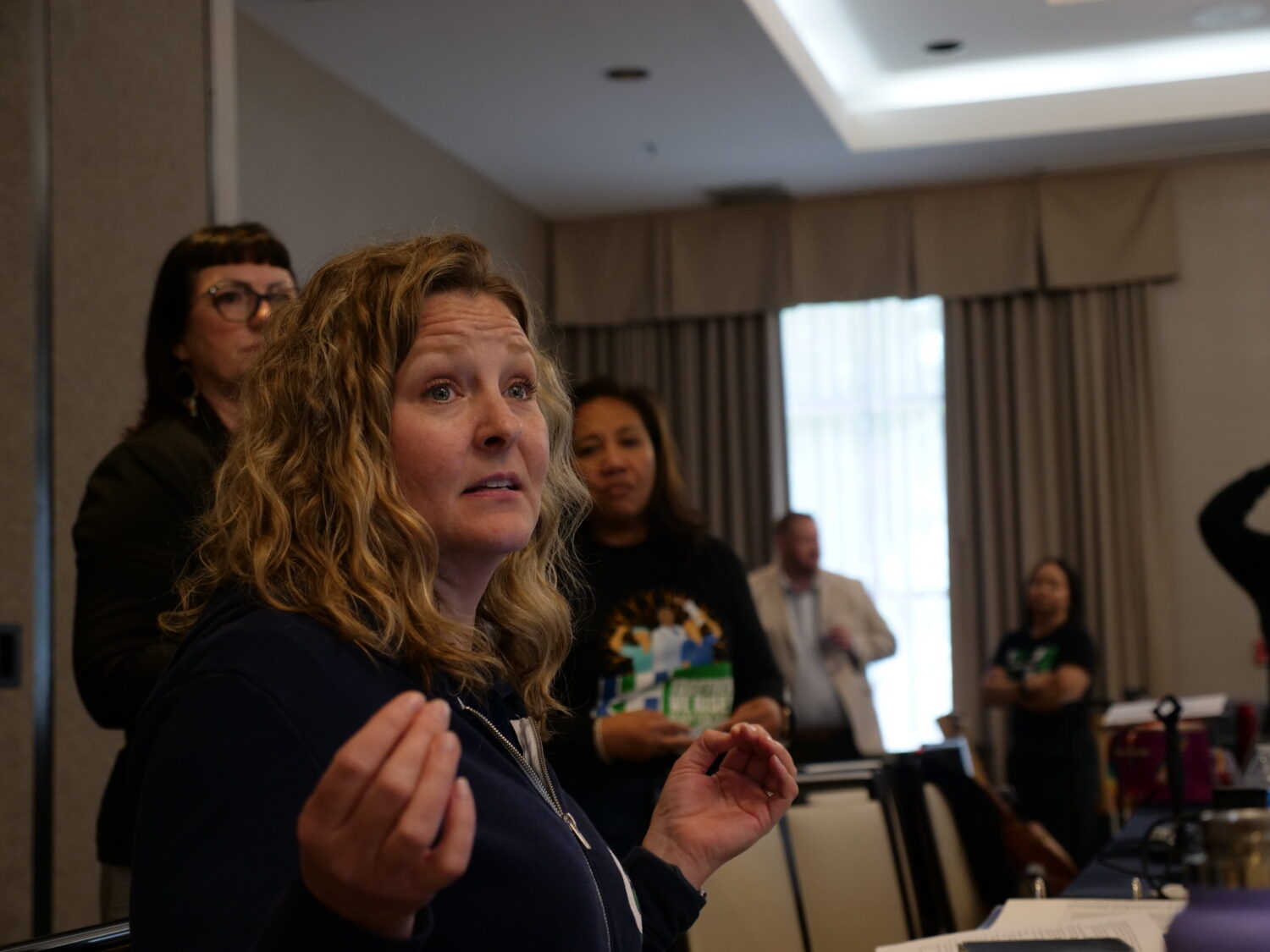 woman speaks to larger group with hand gestures